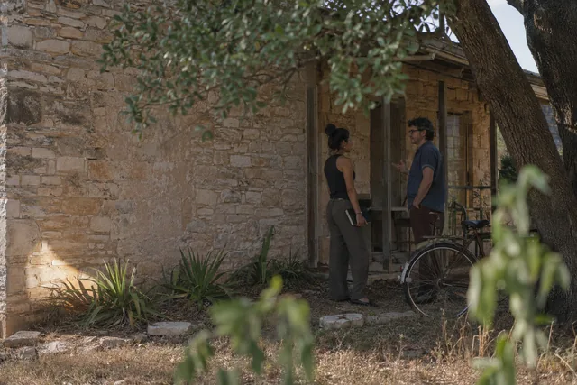 Two writers talk beside a stone porch and a bicycle