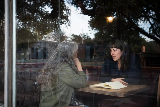 Two writers talk over an open notebook at an Austin cafe