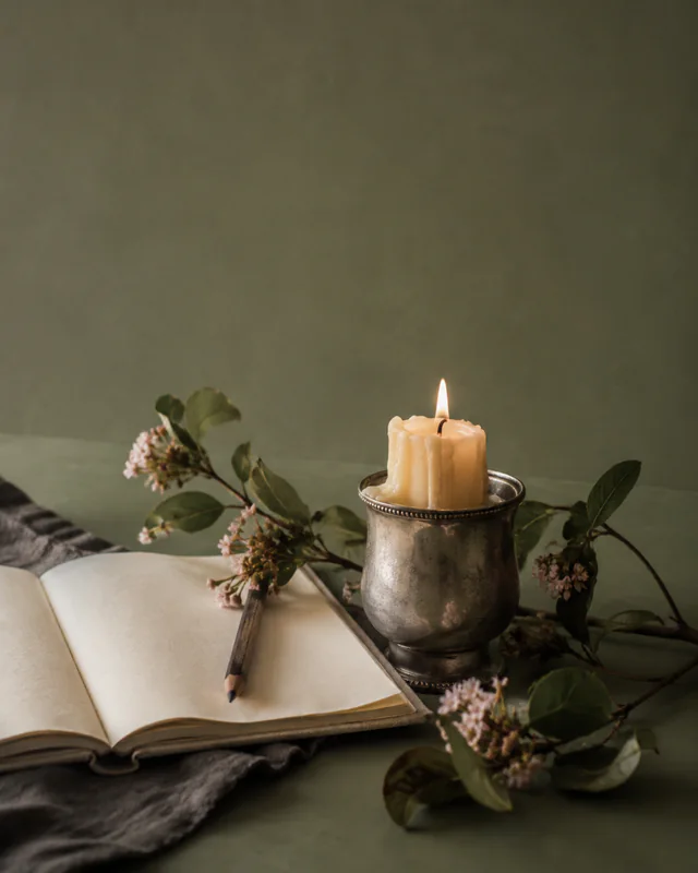 A small candle and notebook arranged on a quiet writing table