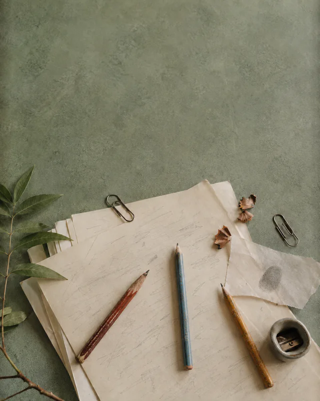 Editing pencils, manuscript pages, clips, and pecan shells on a green table