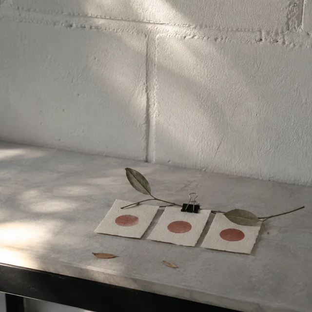 Three rust circles on handmade paper mark a recurring rhythm