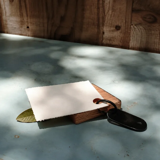A black key rests beside a blank handmade card in afternoon light